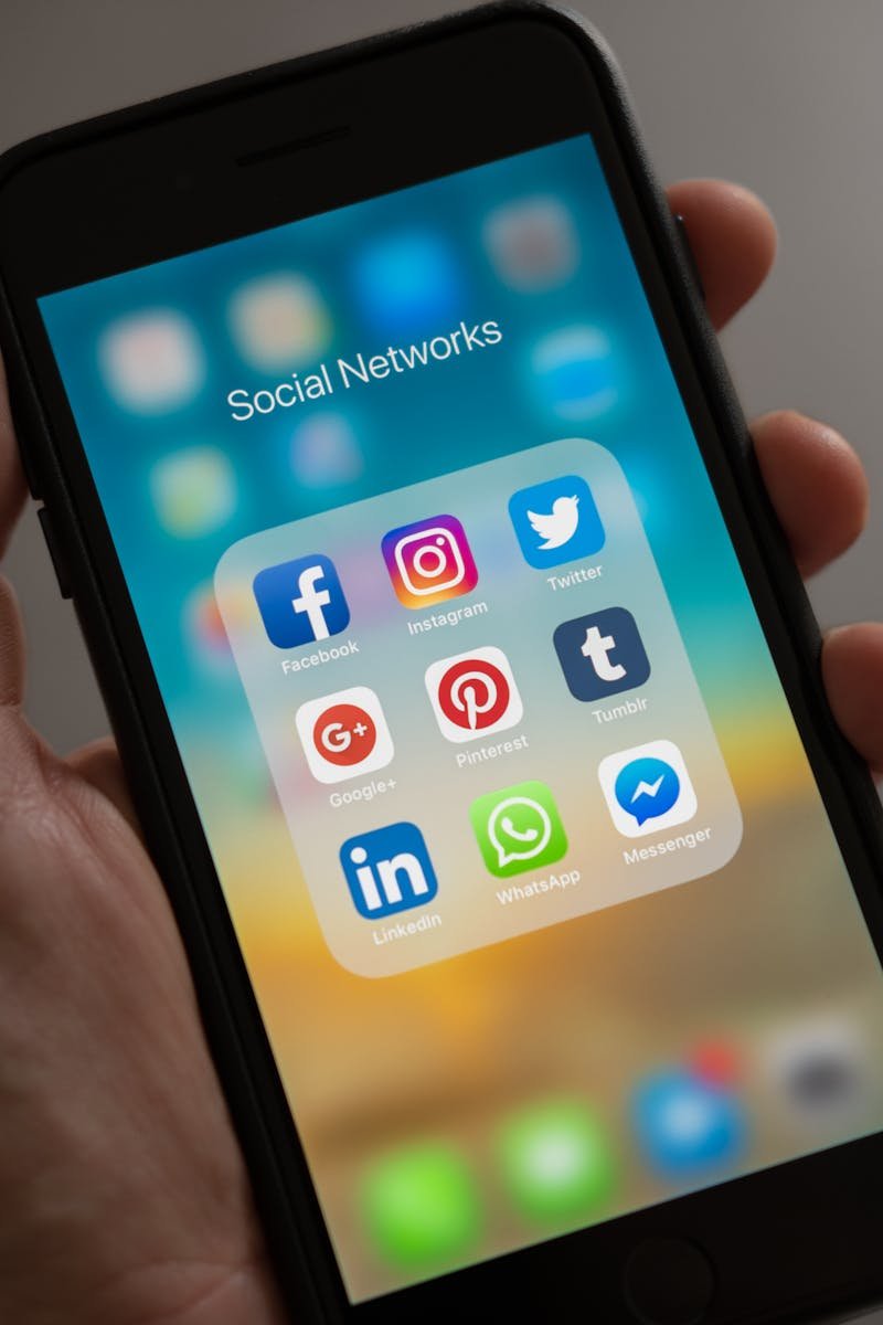 A smartphone displaying various social media icons held in a hand, showcasing modern communication apps.